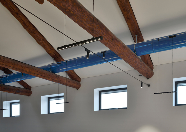 Image of the office with the wooden trusses illuminated with the Funivia system.