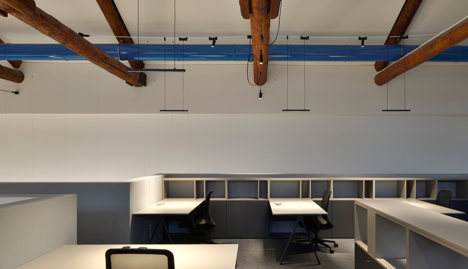 Image of an office with wooden trusses illuminated by Funivia system.