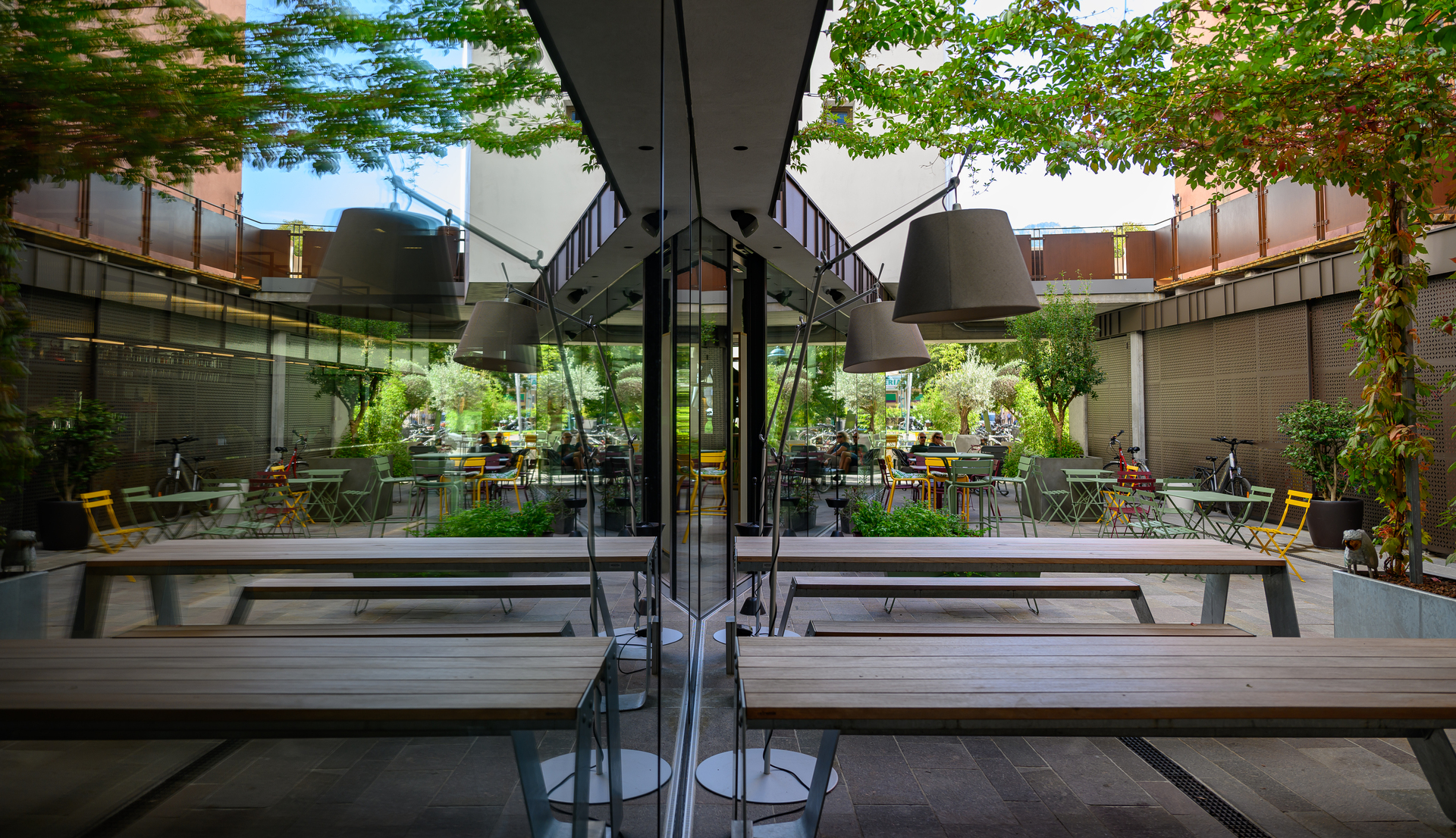 Image of the hotel exterior with benches and tables illuminated by Tolomeo Paralume Outdoor.
